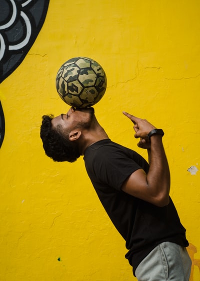 Men's wear black round collar T-shirt, holding a black and white football
